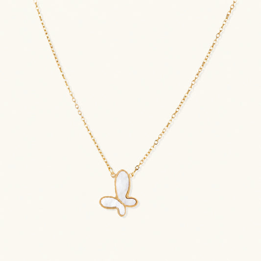 Gold-plated butterfly pendant with iridescent mother of pearl inlay on delicate chain against cream background.