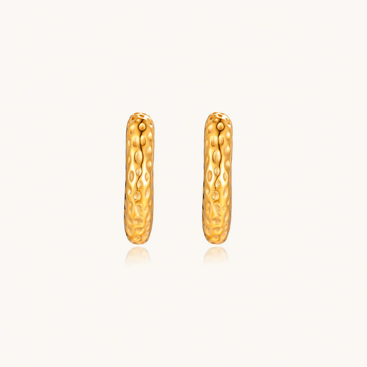 Gold-toned hoop earrings with hammered dimpled texture and post closure on cream background