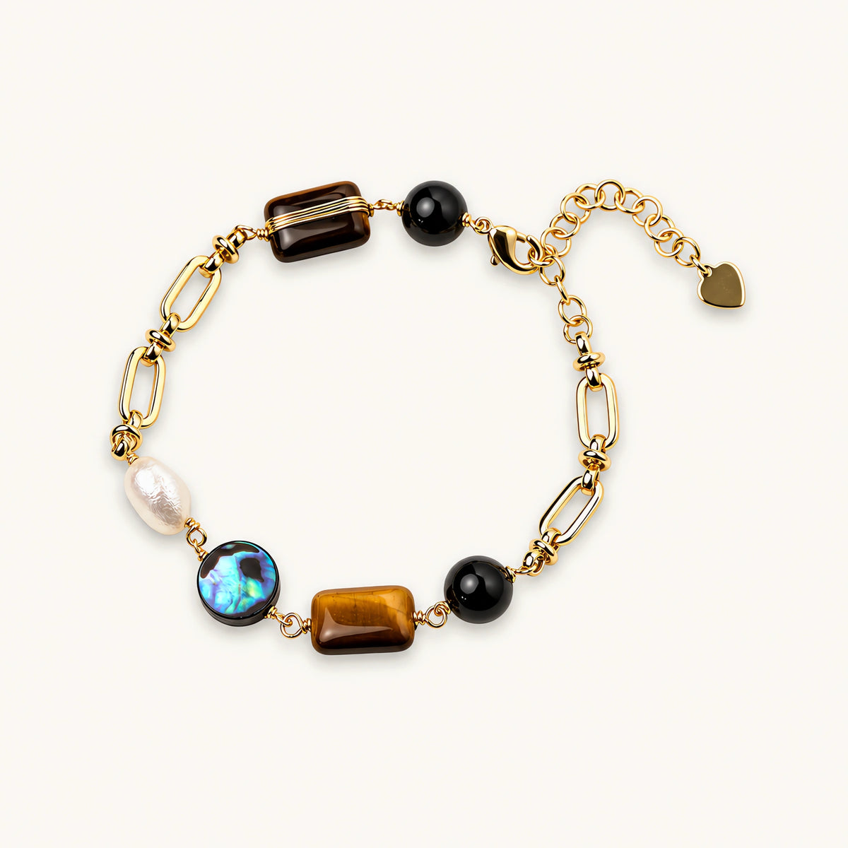 Gold chain bracelet with tiger's eye, obsidian, pearl, and iridescent abalone stones on cream background.